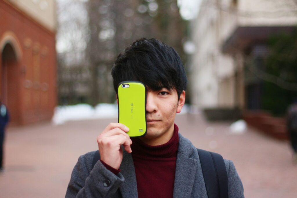 スマホで目を隠す男性