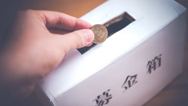 ５００円を白い募金箱に入れようとする左手